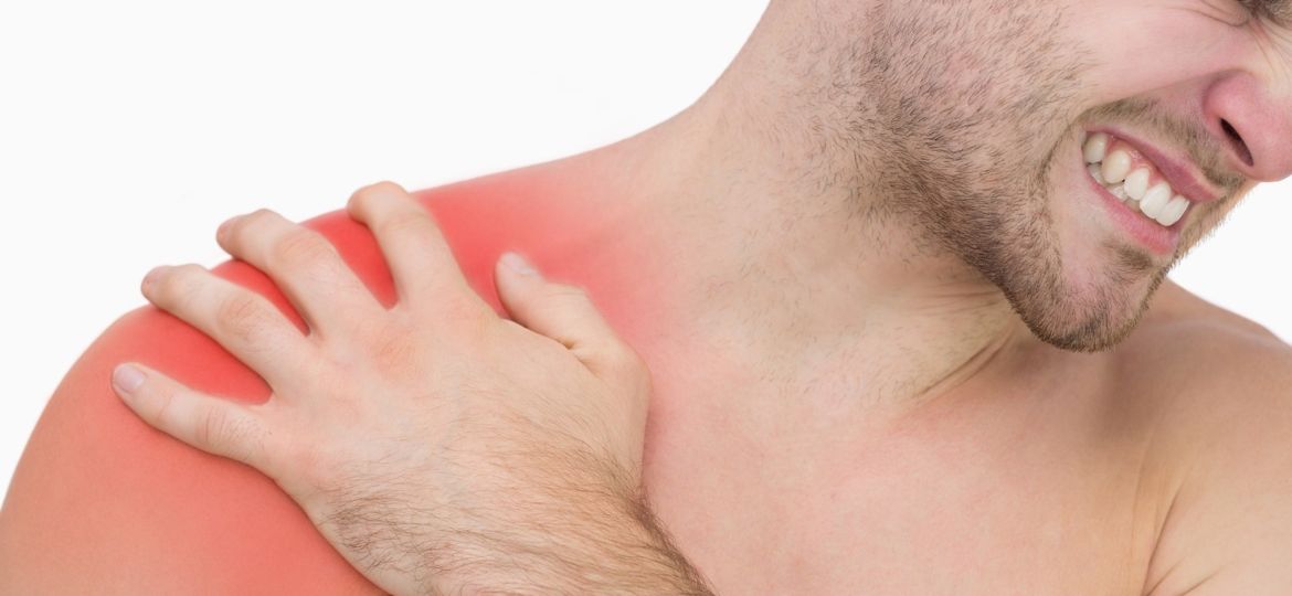 Closeup of young shirtless man with shoulder pain over white bac